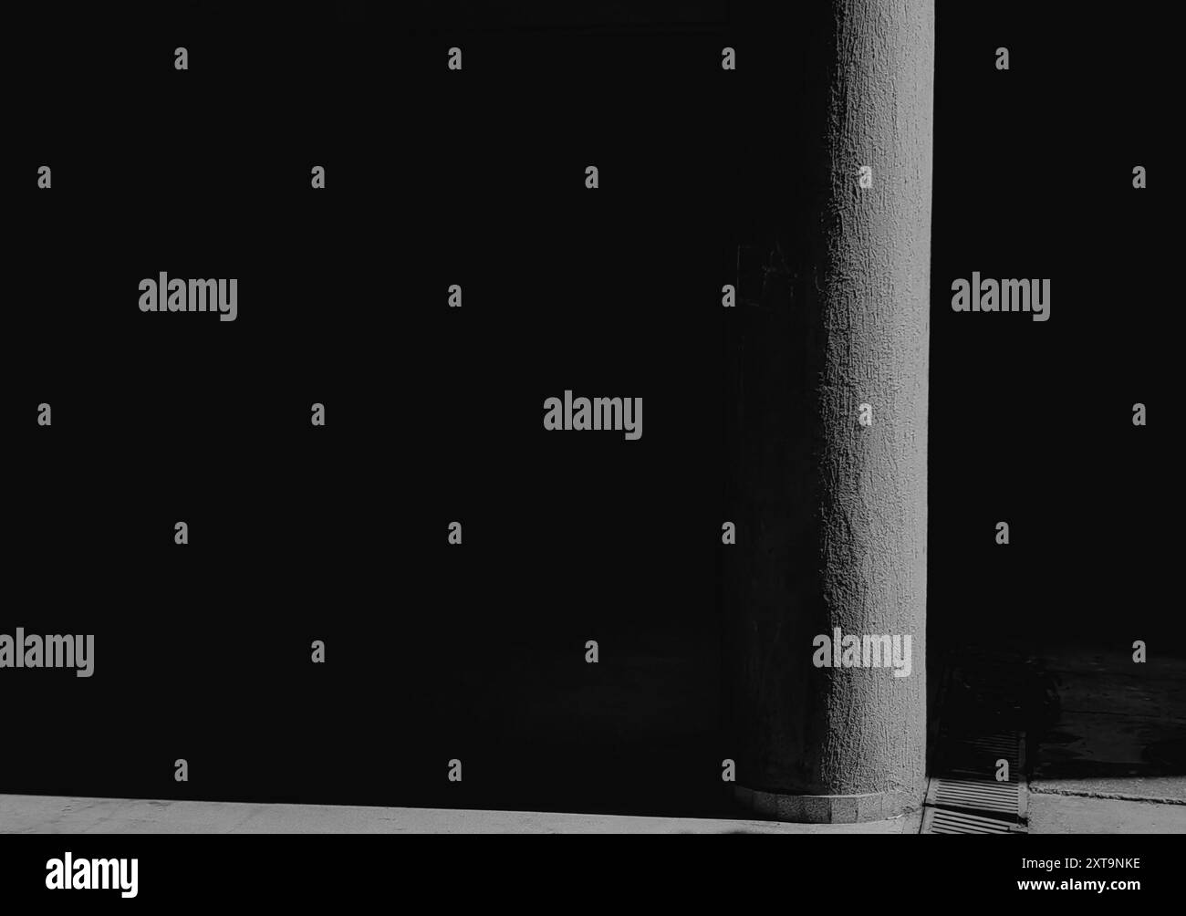 Pilastro in cemento illuminato dal sole: Esplorare l'architettura degli edifici e lo spazio negativo. Bianco e nero. Monocromatico. Minimalismo. Foto Stock