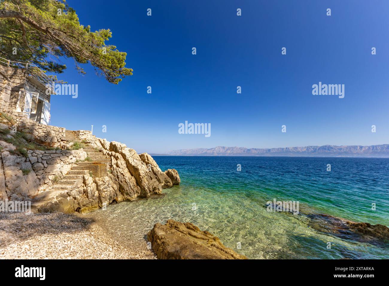 Discesa ripida giù per le scale verso una spiaggia rocciosa, la costa del mare Adriatico in Croazia, ringhiera di sicurezza fatta di spessa fune da pesca Foto Stock