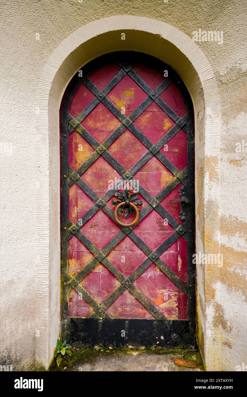 Vecchia porta in metallo arrugginito con un battitoio. Ingresso antico con arco rotondo. Foto Stock