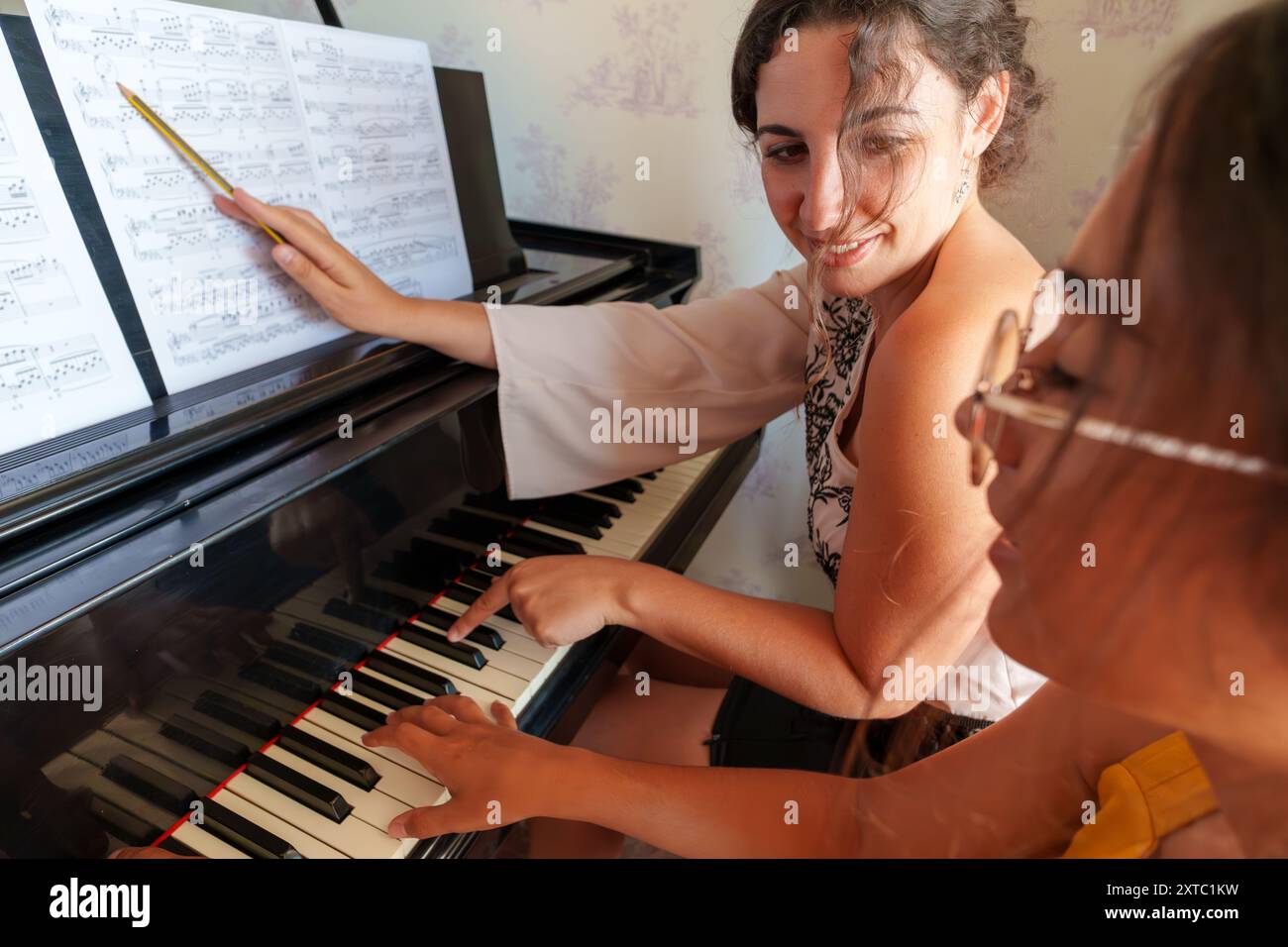 Lezione di pianoforte con insegnante che istruisce lo studente sulla lettura degli spartiti Foto Stock