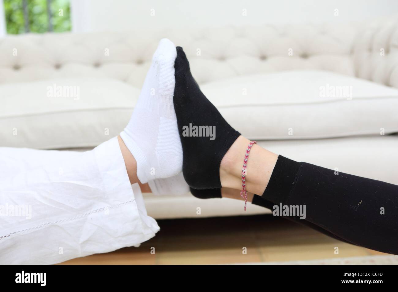 Due ragazze giocano con i piedi calzini bianchi e neri che spingono la suola dei piedi contro l'altra caviglia bracciale Foto Stock