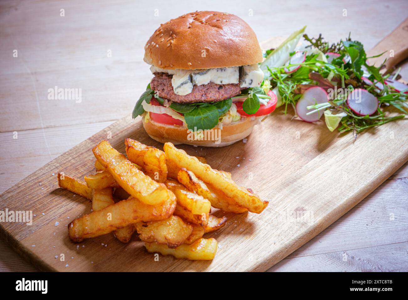 Hamburger di manzo fatto in casa con formaggio blu, patatine fresche fatte in casa e insalata. Foto Stock