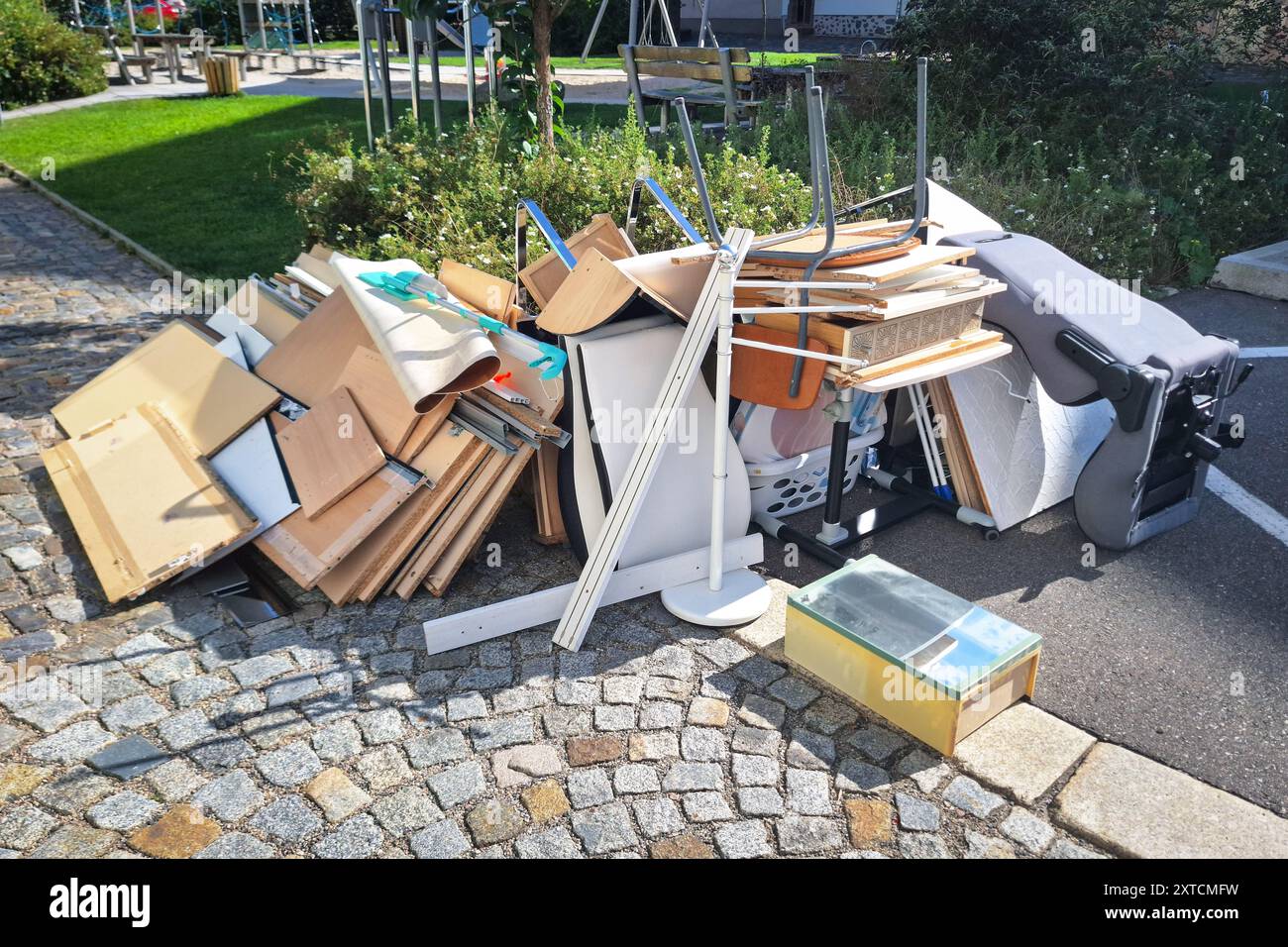 Un mucchio di articoli per la casa e mobili scartati si sono accumulati su una strada acciottolata, raffigurando una giornata di raccolta di rifiuti in una città Foto Stock