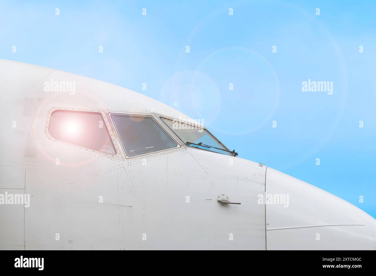Sezione anteriore con ampi finestrini dell'abitacolo della compagnia aerea commerciale e sensori della carrozzeria. Sfondo blu del cielo. Foto Stock