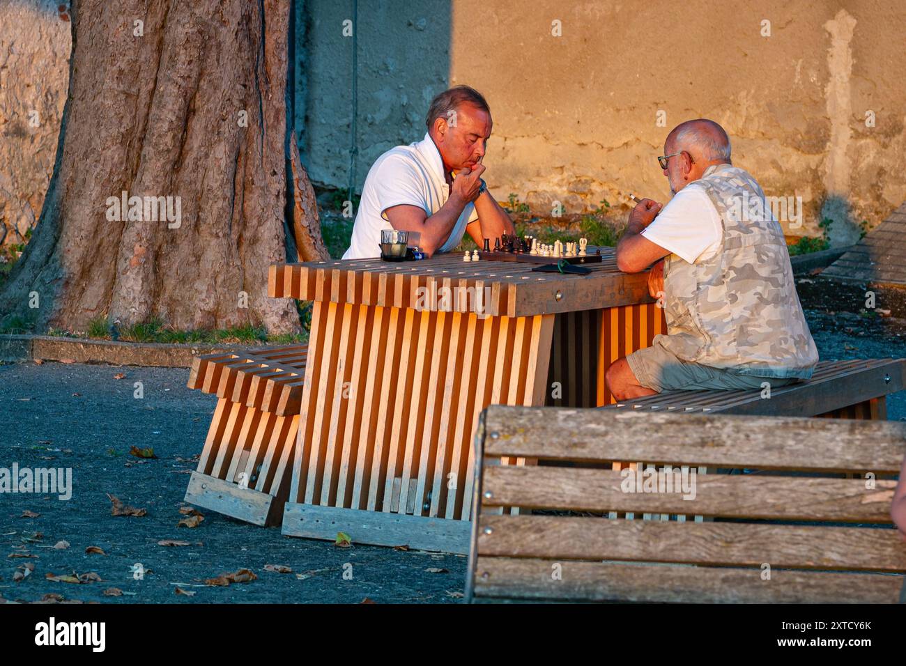 Due persone anziane giocano a scacchi in una serata estiva in Italia. Foto Stock