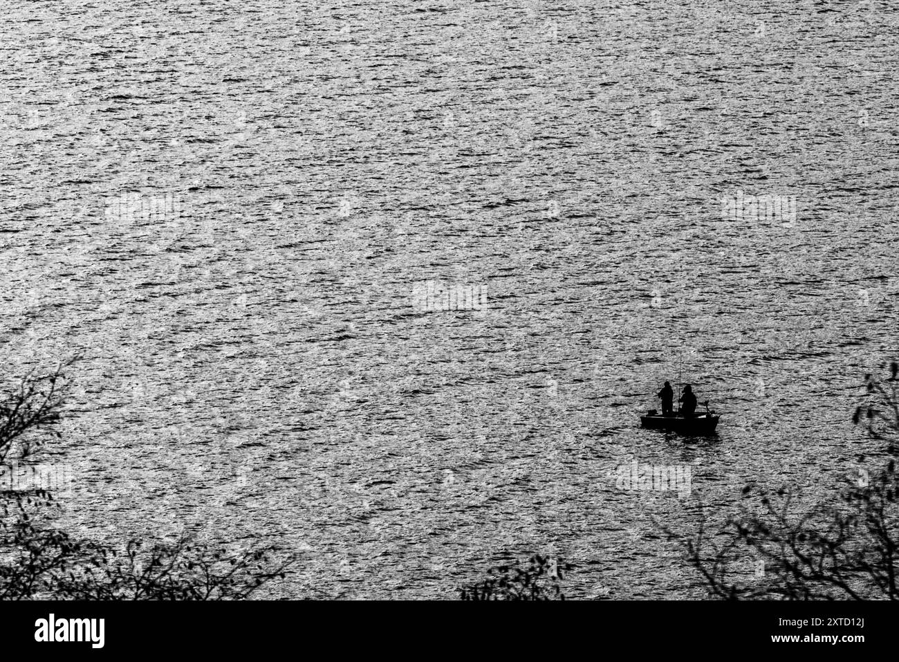 Piccola barca con pescatori nel lago di Lecco in inverno a Lecco in Italia Foto Stock