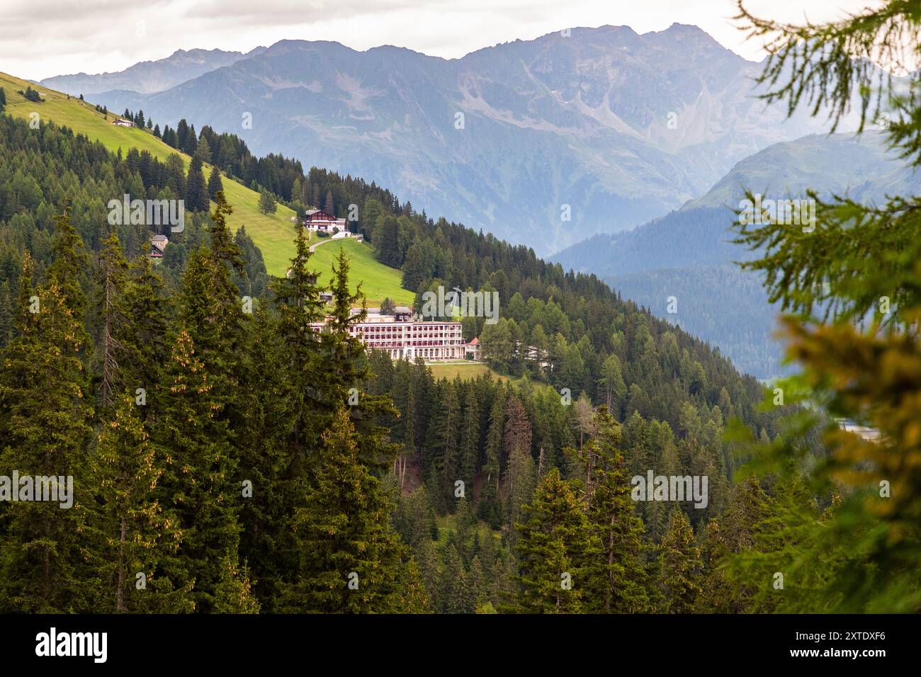 Il Berghotel Schatzalp si erge su una cresta montuosa boscosa sopra Davos, visto qui dal sentiero circolare della cascata, circondato da foreste di conifere e dalle vette frastagliate delle Alpi retiche. L’hotel è stato costruito nel 1898–1900 da Otto Pfleghard e Max Haefeli come sanatorio di lusso per Willem Jan Holsboer. Erbalpweg, Davos, Grigioni, Svizzera. Foto Stock