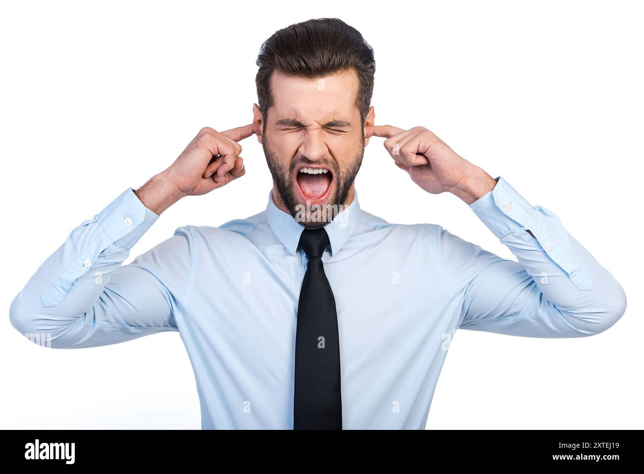 Suono troppo forte! Giovane frustrato in camicia e cravatta che copre le orecchie con le dita e tiene gli occhi chiusi mentre si trova su sfondo bianco Foto Stock Suono troppo forte! Giovane frustrato in camicia e cravatta che copre le orecchie con le dita e tiene gli occhi chiusi mentre si trova su sfondo bianco Foto Stock