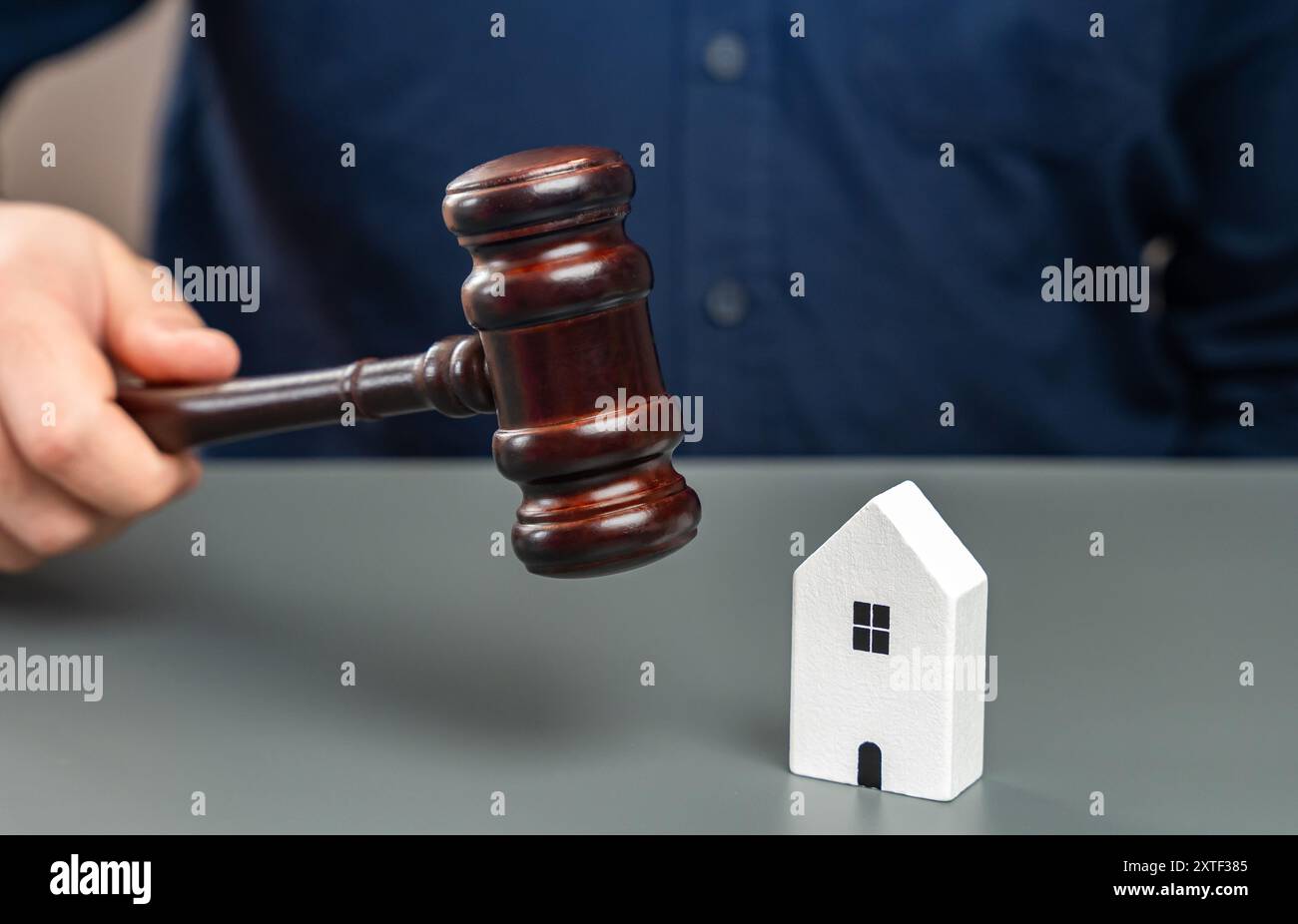 Una statuetta di una casa e un uomo con un martelletto di giudici. Decisioni del tribunale immobiliare. Contenzioso sull'eredità di proprietà. Costituzione della proprietà. Amnistia Foto Stock