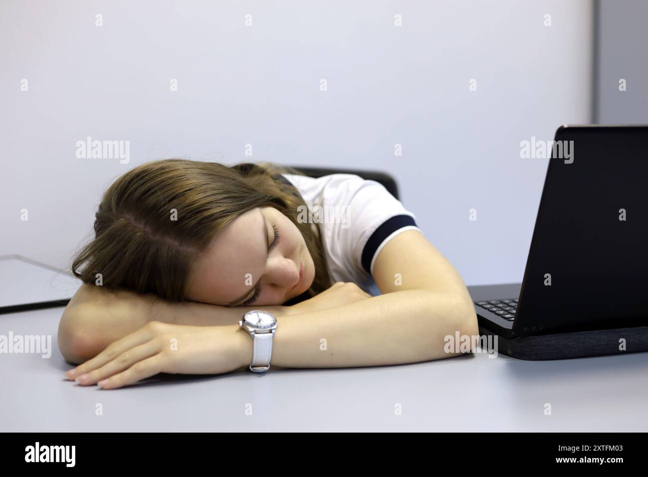 Ragazza che dorme vicino al portatile al tavolo dell'ufficio. Concetto di dipendente sovraccarico, stanco dopo il lavoro, notte insonne Foto Stock