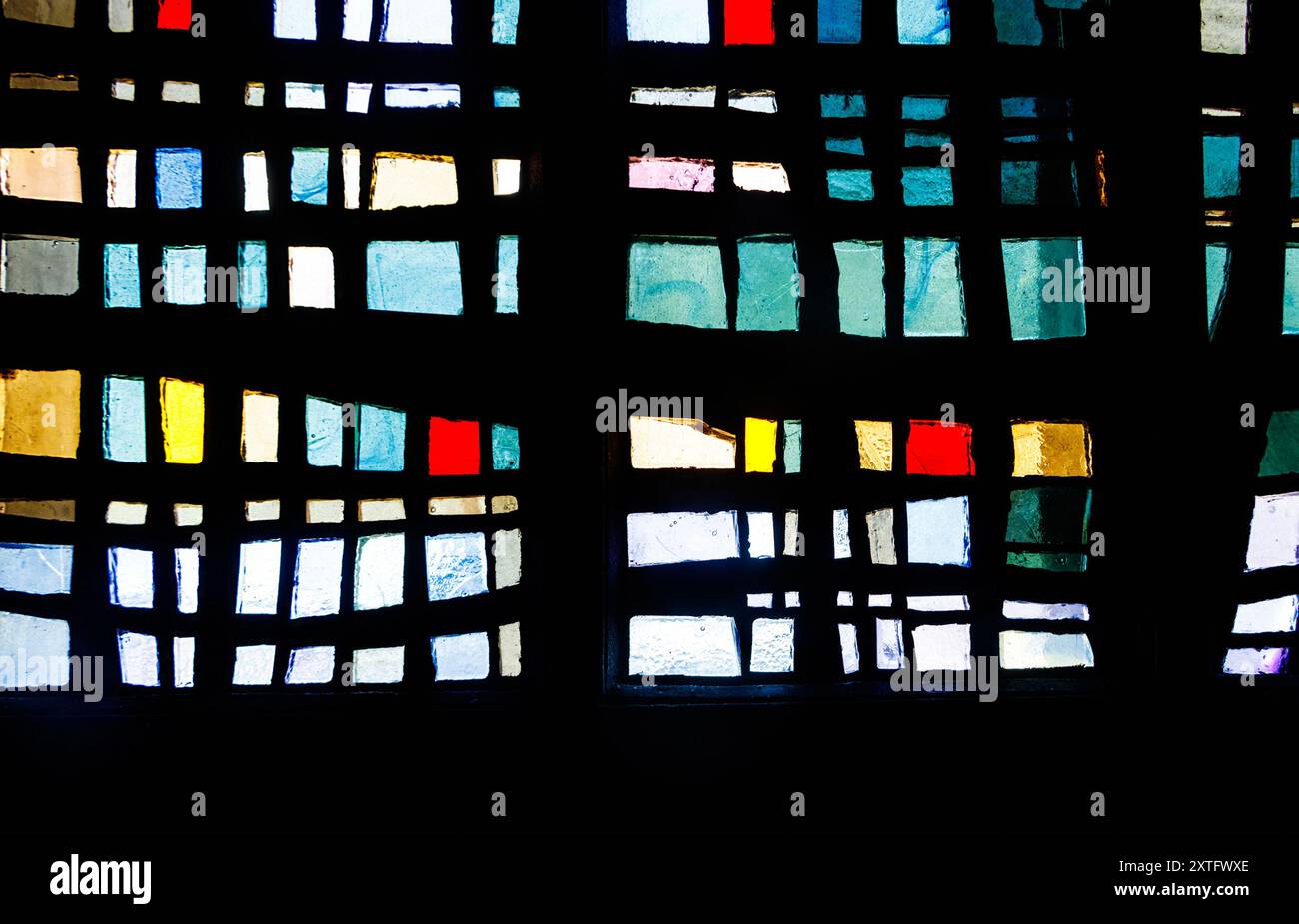 Finestra in vetro colorato astratto con motivi colorati rettangolari e quadrati in tonalità di blu, rosso, verde, giallo e nero. Foto Stock
