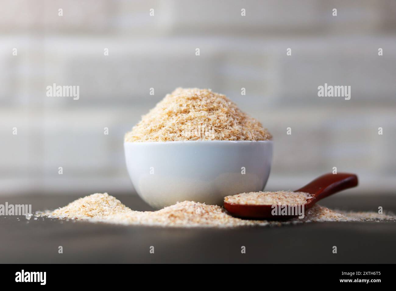 Psyllium Husk (Isabgol) in una ciotola con un cucchiaio di legno su sfondo nero Foto Stock
