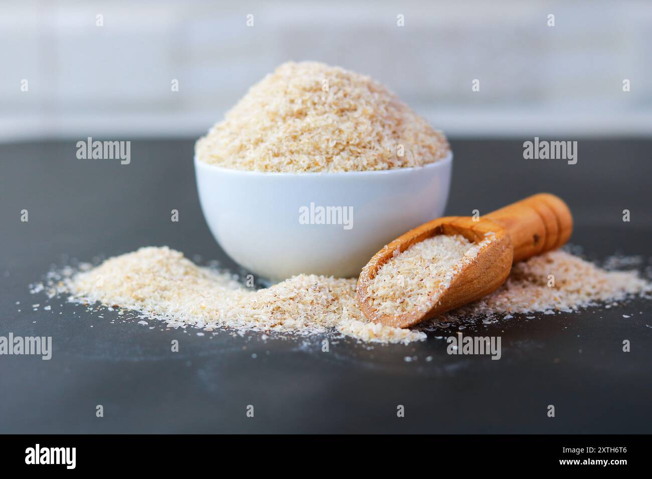 Psyllium Husk (Isabgol) in una ciotola con un cucchiaio di legno su sfondo nero Foto Stock