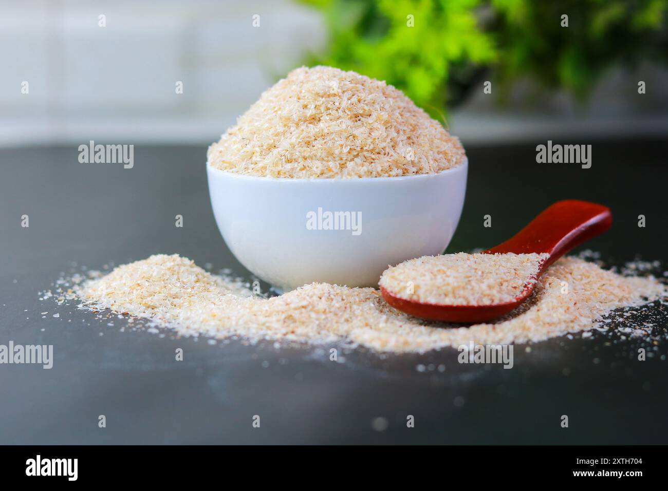 Psyllium Husk (Isabgol) in una ciotola con un cucchiaio di legno su sfondo nero Foto Stock