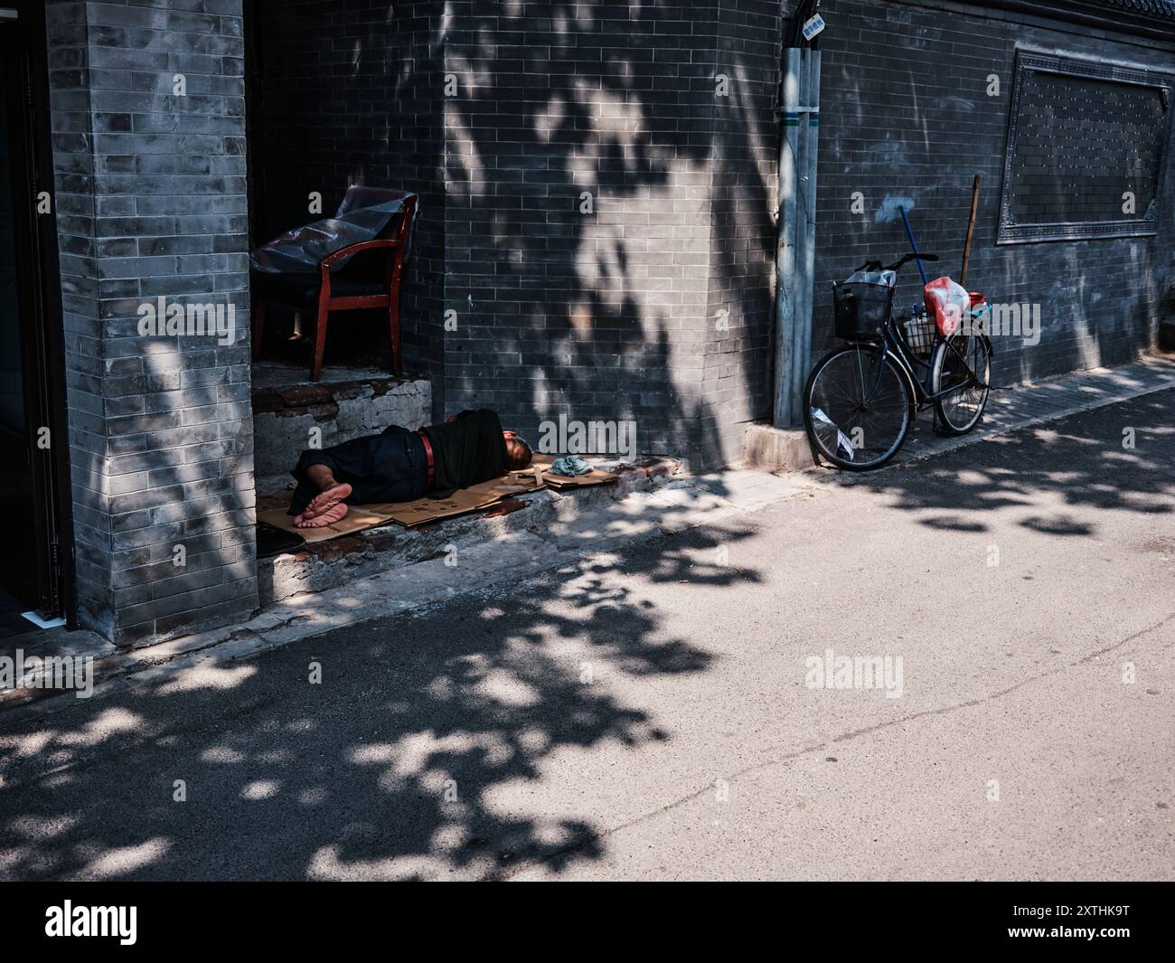 Un lavoratore senza tetto dorme in strada a Pechino Foto Stock