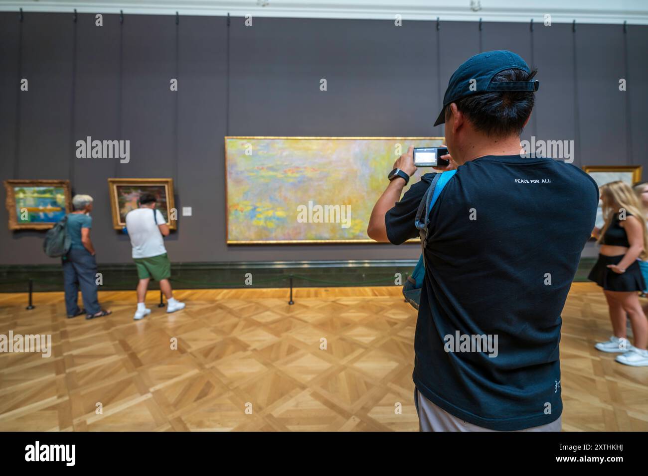 Gli interni della London National Gallery, un museo d'arte londinese a Trafalgar Square. Visitatore all'interno che scatta una foto di pittura con PACE PER TUTTI sulla sua camicia. Foto Stock