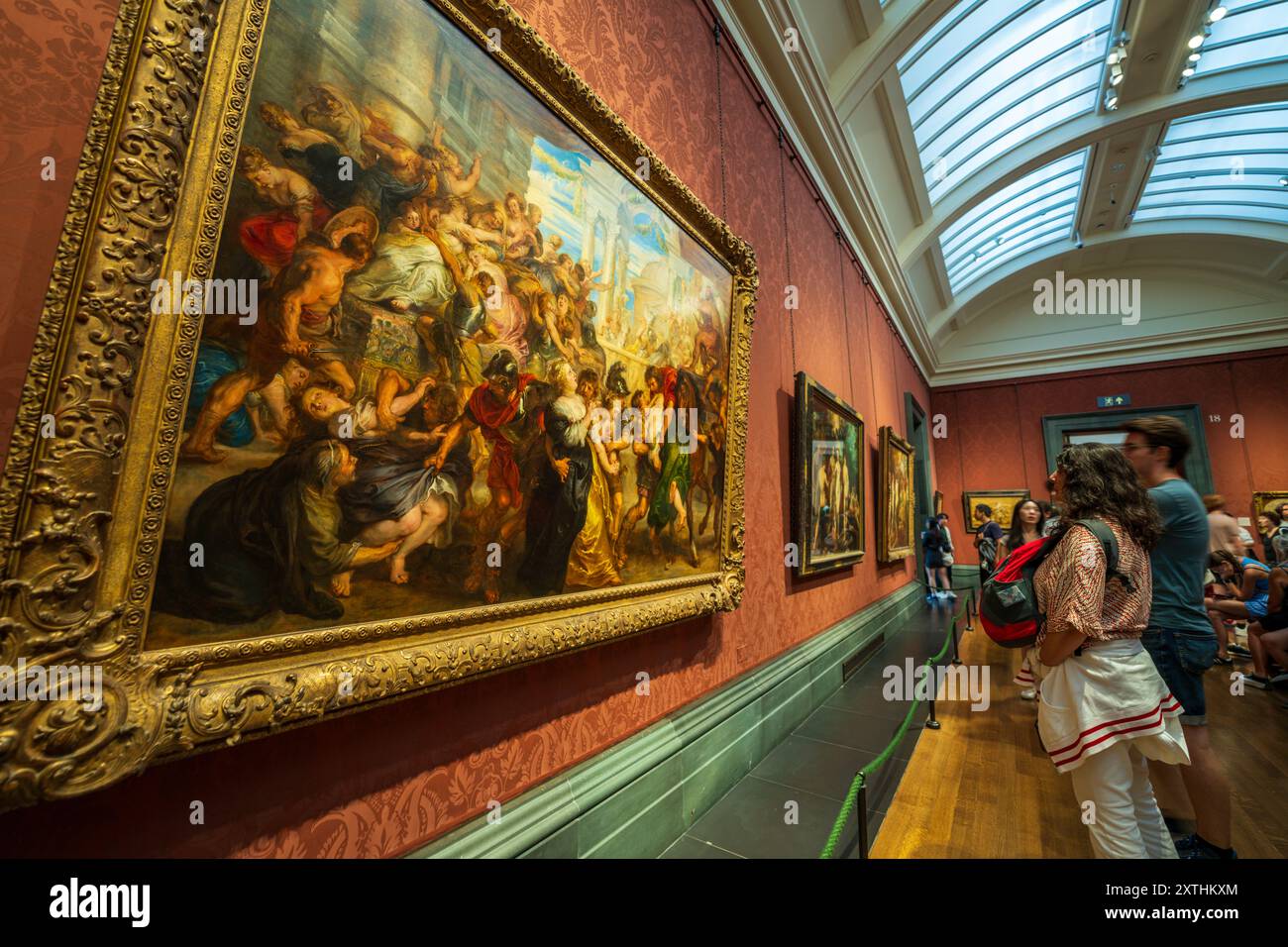Stile di vita e cultura londinesi. Persone che guardano un grande dipinto su un muro nel museo d'arte della National Gallery. I visitatori in vacanza godendo di opere d'arte. Foto Stock