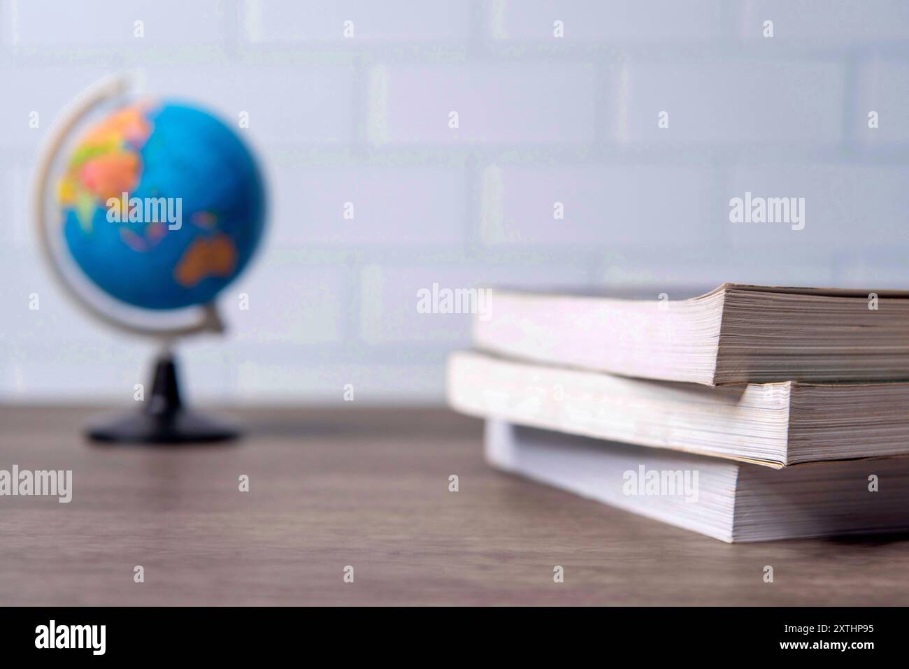 Un primo piano di un globo accanto a una pila di libri su un tavolo di legno. Copia spazio per il testo. Conoscenza, apprendimento ed esplorazione. Foto Stock