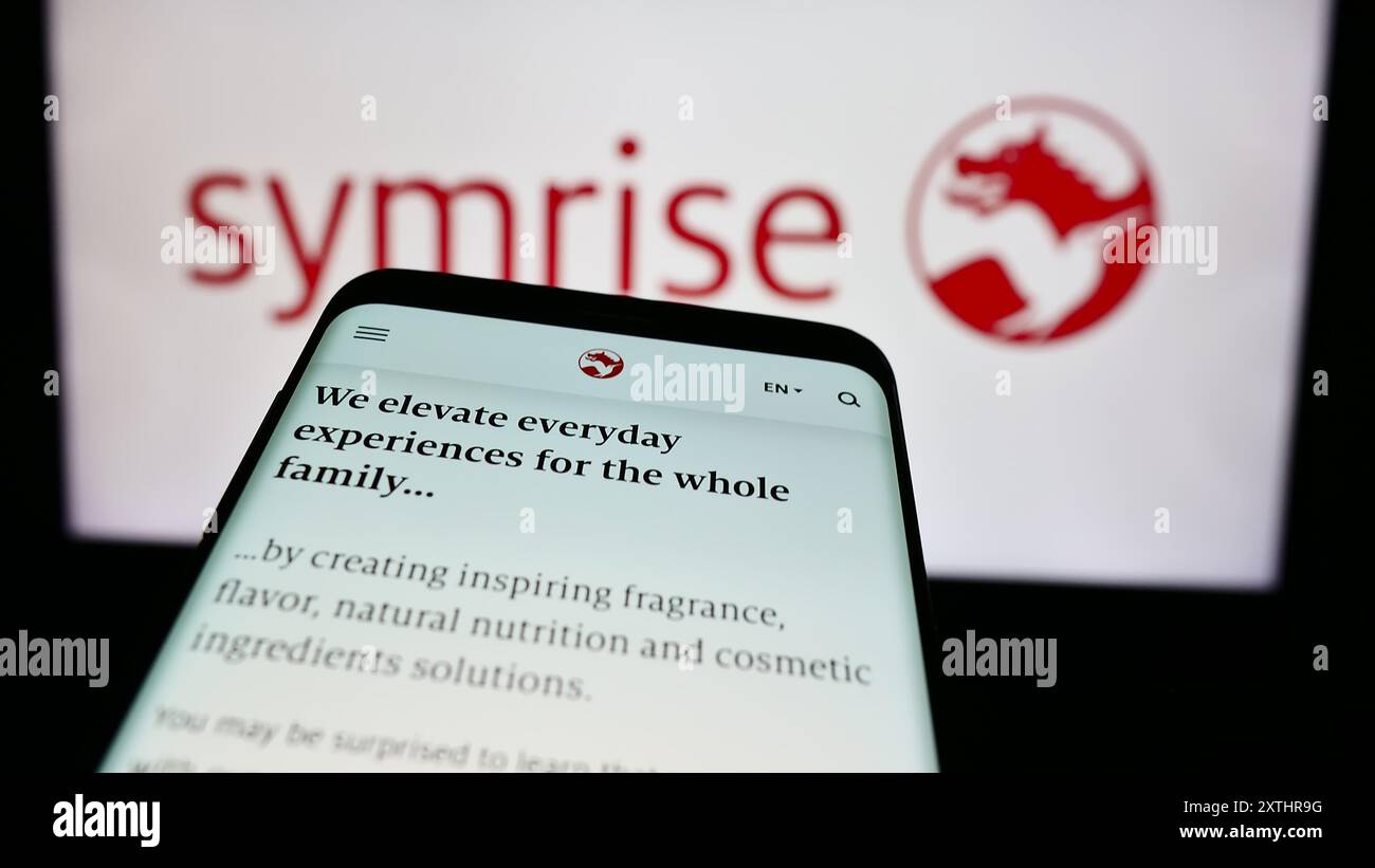 Telefono cellulare con pagina web dell'azienda tedesca Symrise AG di sapori e profumi davanti al logo aziendale. Mettere a fuoco in alto a sinistra sul display del telefono. Foto Stock