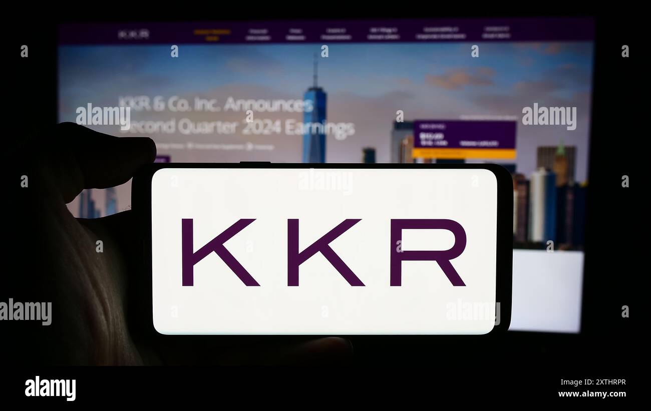 Persona che detiene un cellulare con il logo della società di investimento statunitense KKR Co. Inc. Di fronte alla pagina web aziendale. Mettere a fuoco il display del telefono. Foto Stock