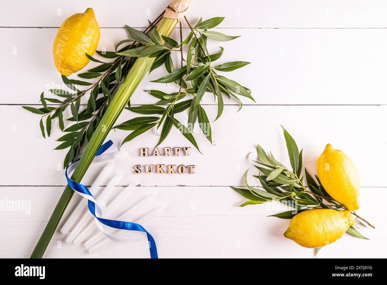 Un contesto festivo per il festival ebraico di Sukkot con simboli e candele tradizionali. sfondo bianco in legno. Lettere di legno del Sukkot. Foto Stock