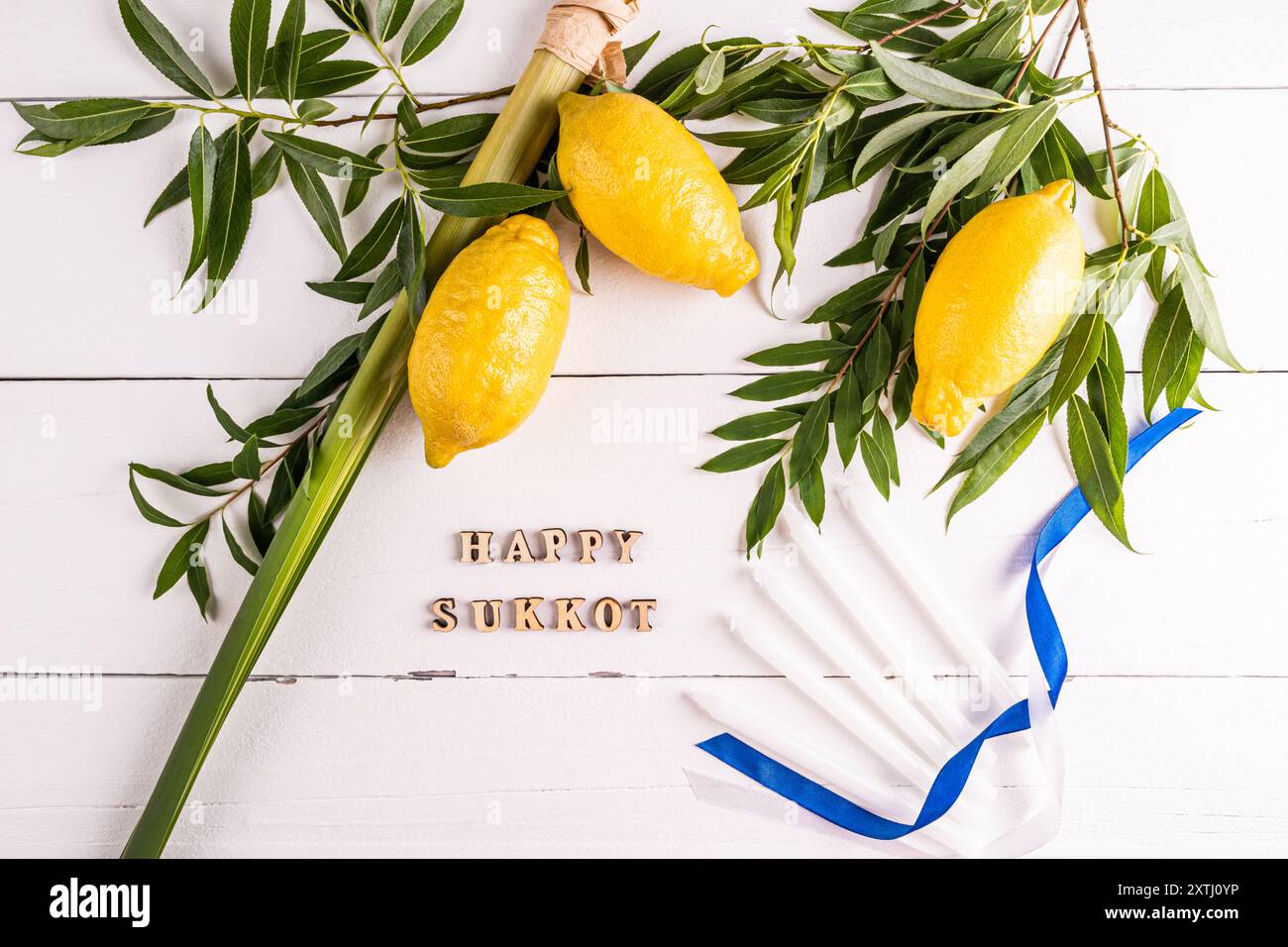 Un bellissimo sfondo festivo per la festa del raccolto ebraico di Sukkot con simboli e candele tradizionali. Lettere di legno del Sukkot. Foto Stock
