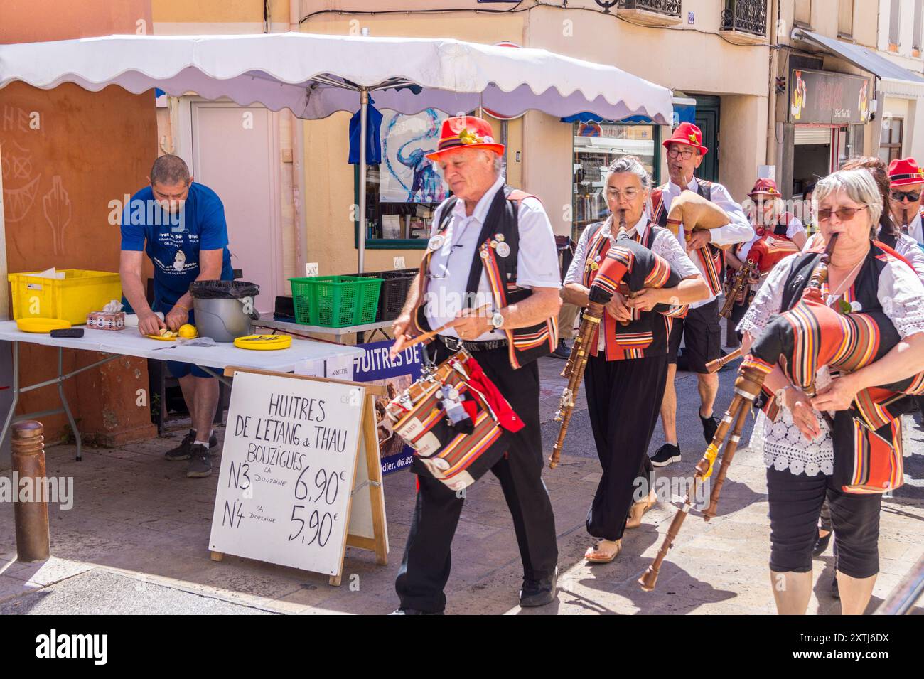 Una band che suona timbal e SAC de gemecs al mercato di strada, Elne, Pyrénées Orientales, Occitanie, Francia vendendo ostriche da Etang de Thau Foto Stock