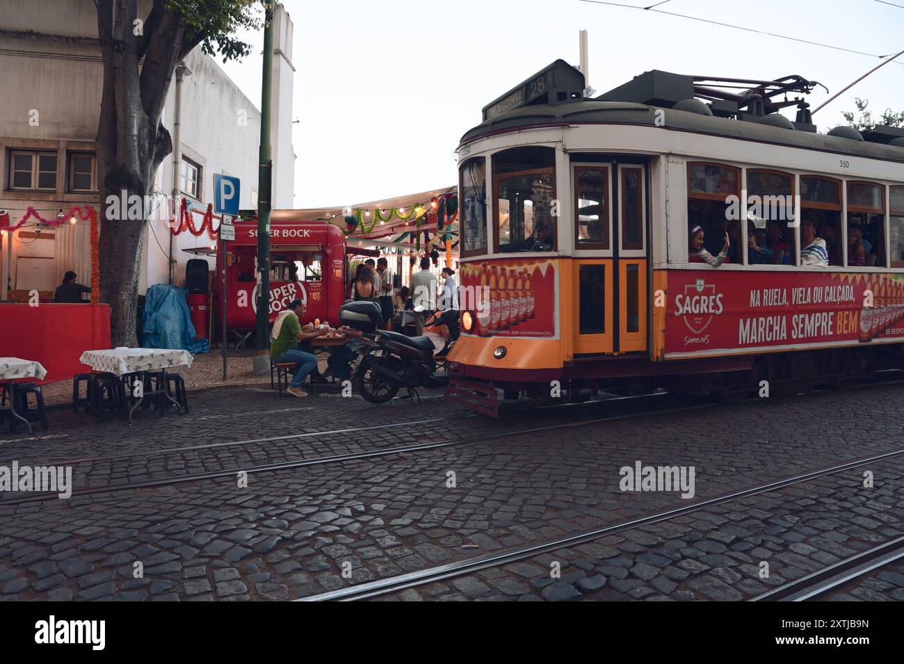 La famosa festa dei santi di Lisbona, vivace strada con l'iconico tram 28 Foto Stock