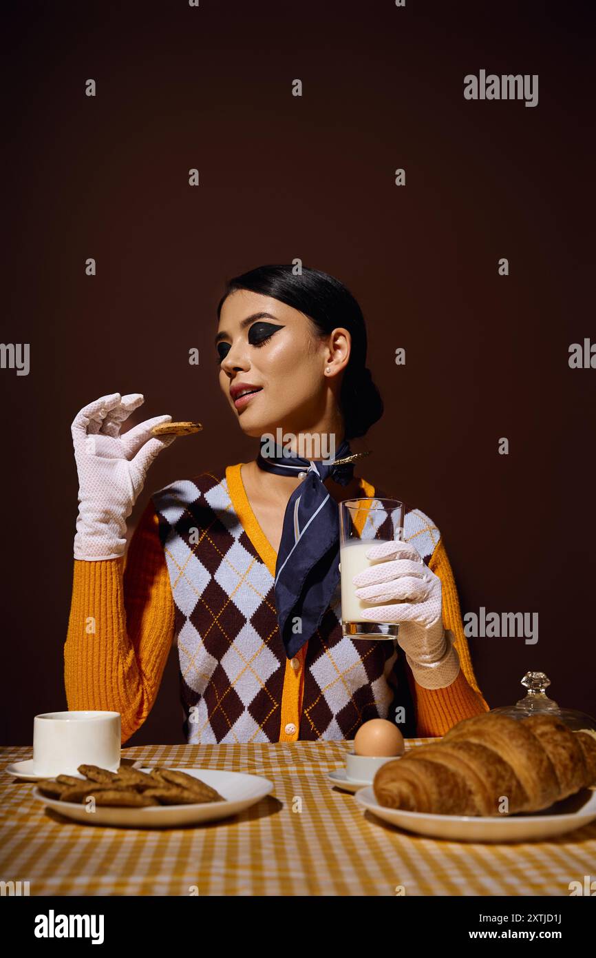 Una giovane donna, vestita con abiti alla moda, gode di una piacevole colazione. Foto Stock