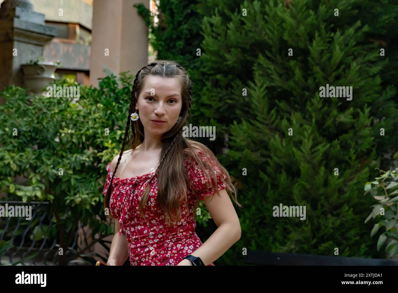 Una giovane donna spensierata con i capelli rossi balla con il suo smartphone in mano, godendosi il sole e guardando la fotocamera, catturando un momento vivace. Foto Stock