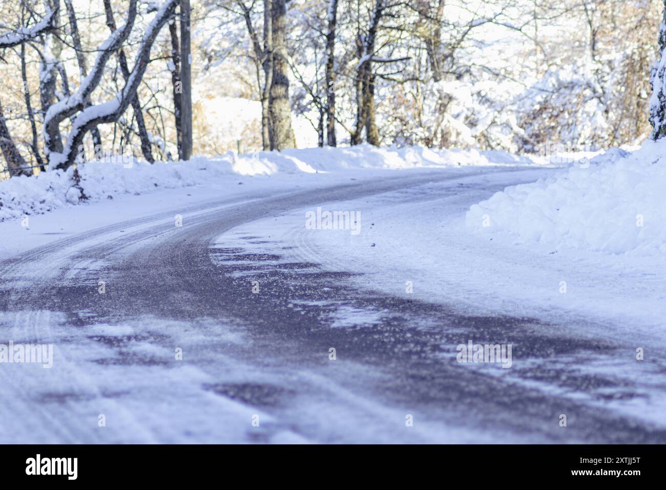 Una strada vuota con una difficile svolta a sinistra coperta di neve. Viaggio su strada, guida estrema, sicurezza sulle strade e conservazione dell'ambiente. Foto Stock