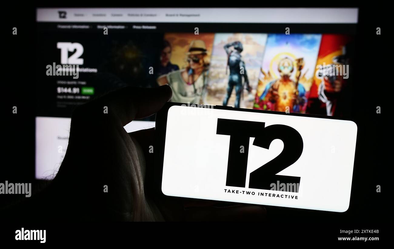 Persona che possiede uno smartphone con il logo della società di gioco statunitense Take-Two Interactive software Inc. Davanti al sito Web. Mettere a fuoco il display del telefono. Foto Stock
