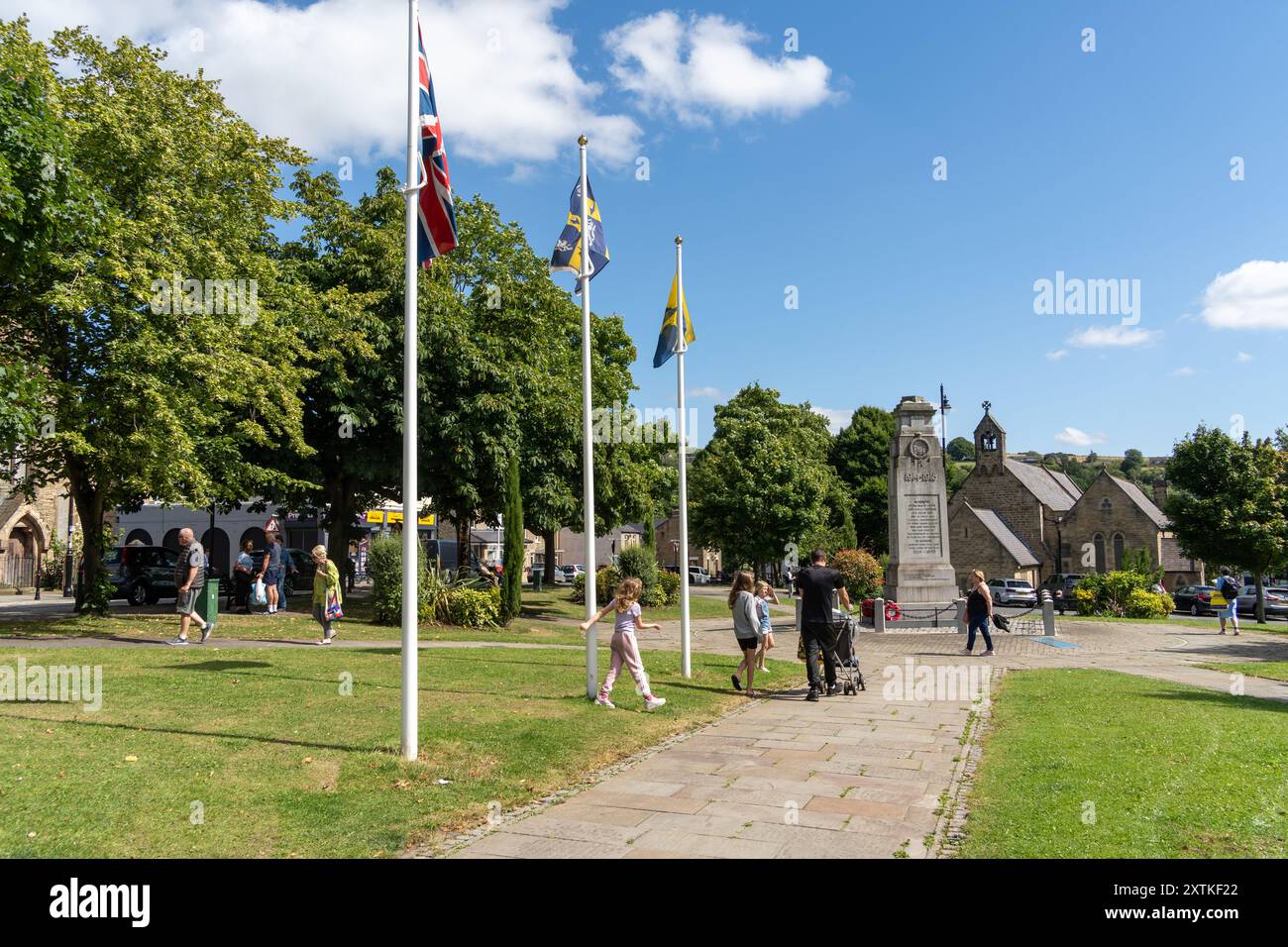 Crook, Contea di Durham, Regno Unito. Piazza del mercato e giardini nel centro della città con pali di bandiera e memoriale di guerra. Foto Stock