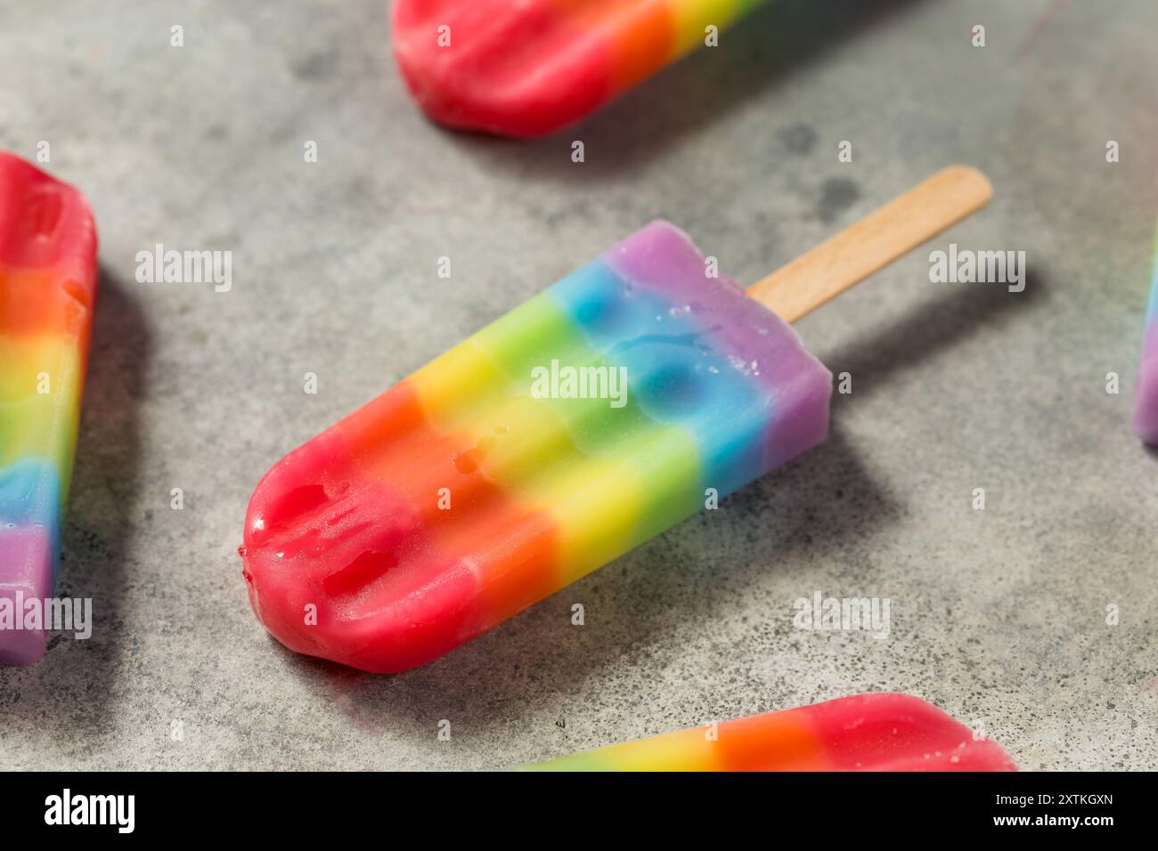 Dolci papaveri arcobaleno estivi con diversi sapori di frutta, disposti su sfondo grigio Foto Stock