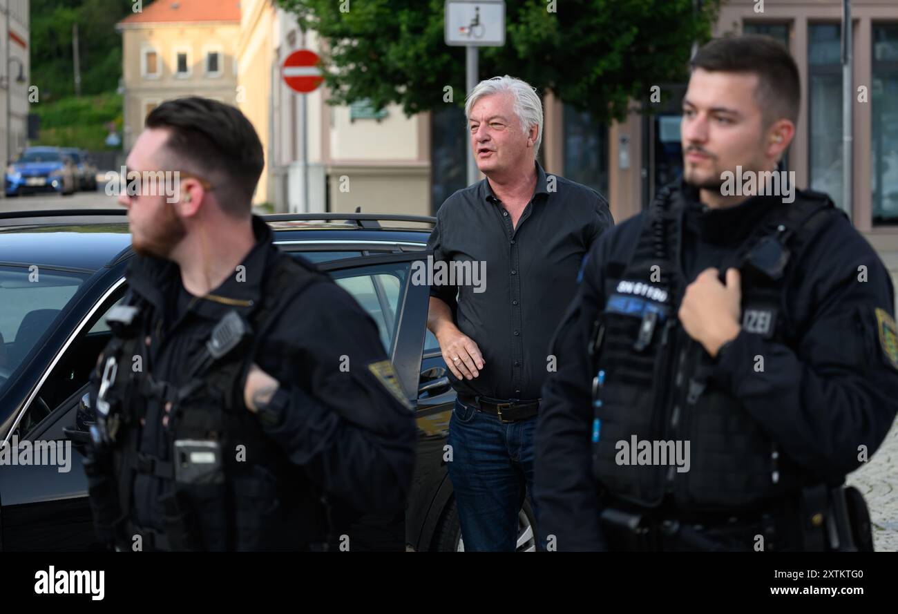 Sebnitz, Germania. 15 agosto 2024. Jürgen Elsässer (M), caporedattore di Compact, entra nella piazza del mercato prima dell'inizio di un evento AfD, con agenti di polizia davanti a lui. Il capo della società dei media estremisti di destra vede la sentenza del tribunale a favore del suo documento come una vittoria contro l'interferenza statale. Crediti: Robert Michael/dpa/Alamy Live News Foto Stock