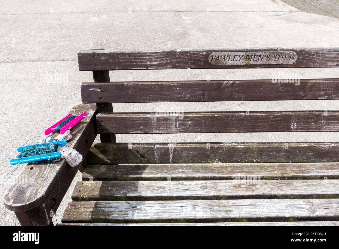 Panchina in legno sul mare o sul porto di Ashlett Creek con una targa che mostra che è stata realizzata da Fawley Men's Shed, Hampshire, Inghilterra, Regno Unito Foto Stock