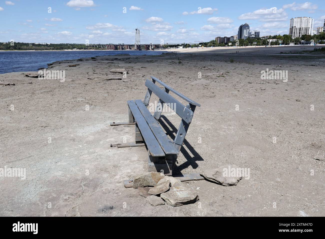Una panchina di riposo è vista sulla riva come l'acqua nel fiume Dnipro è caduta più di 5,5 metri dopo l'esplosione della diga di Kakhovka. La riva del fiume Dnipro ha iniziato a prosciugarsi ancora una volta (estate 2024). Il livello dell'acqua nel fiume sta diminuendo a causa del calore anomalo e dei problemi legati all'esplosione della diga di Kakhovskaja (giugno 2023). Gli ecologisti sono sicuri che la riduzione dell'acqua nel Dnipro avrà un effetto negativo sui pesci nel serbatoio. Foto Stock