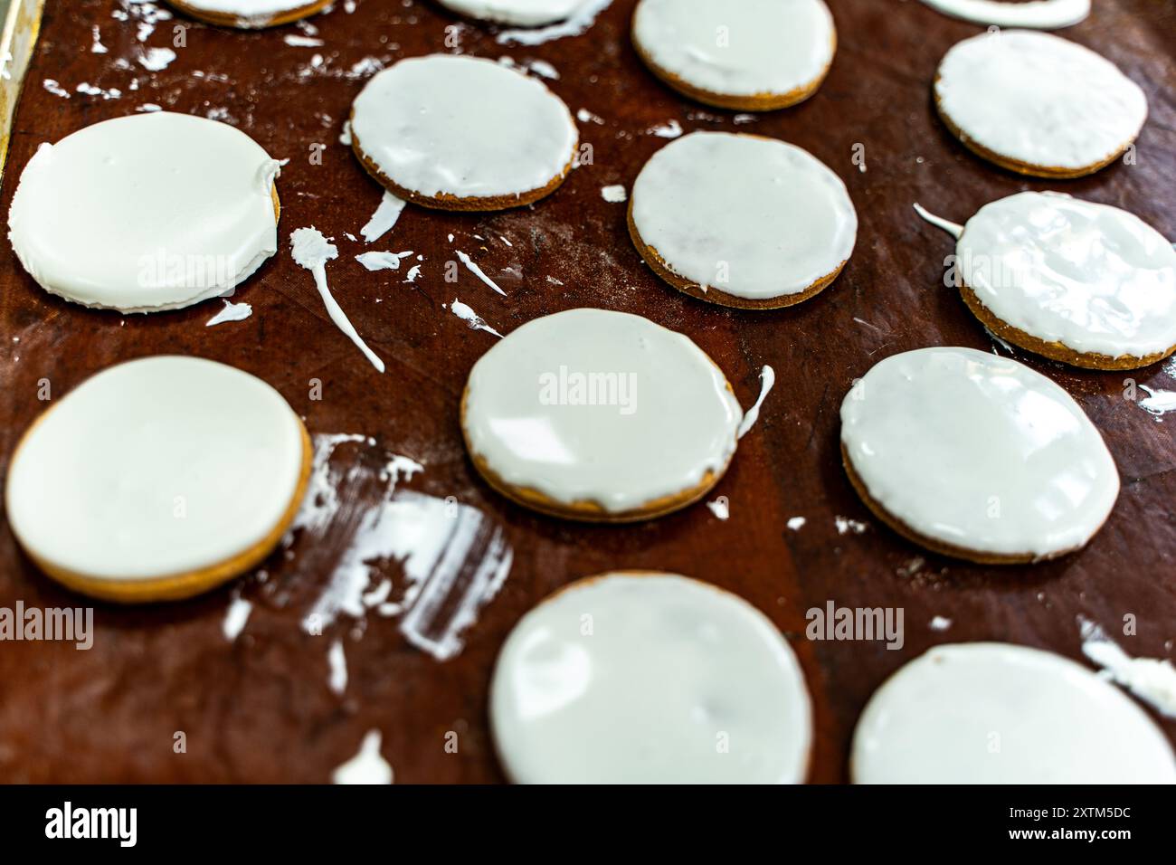 Biscotti con glassa bianca su una teglia da forno. Produzione di biscotti. Mini panificio o linea di produzione industriale per prodotti a base di farina. Foto di alta qualità Foto Stock