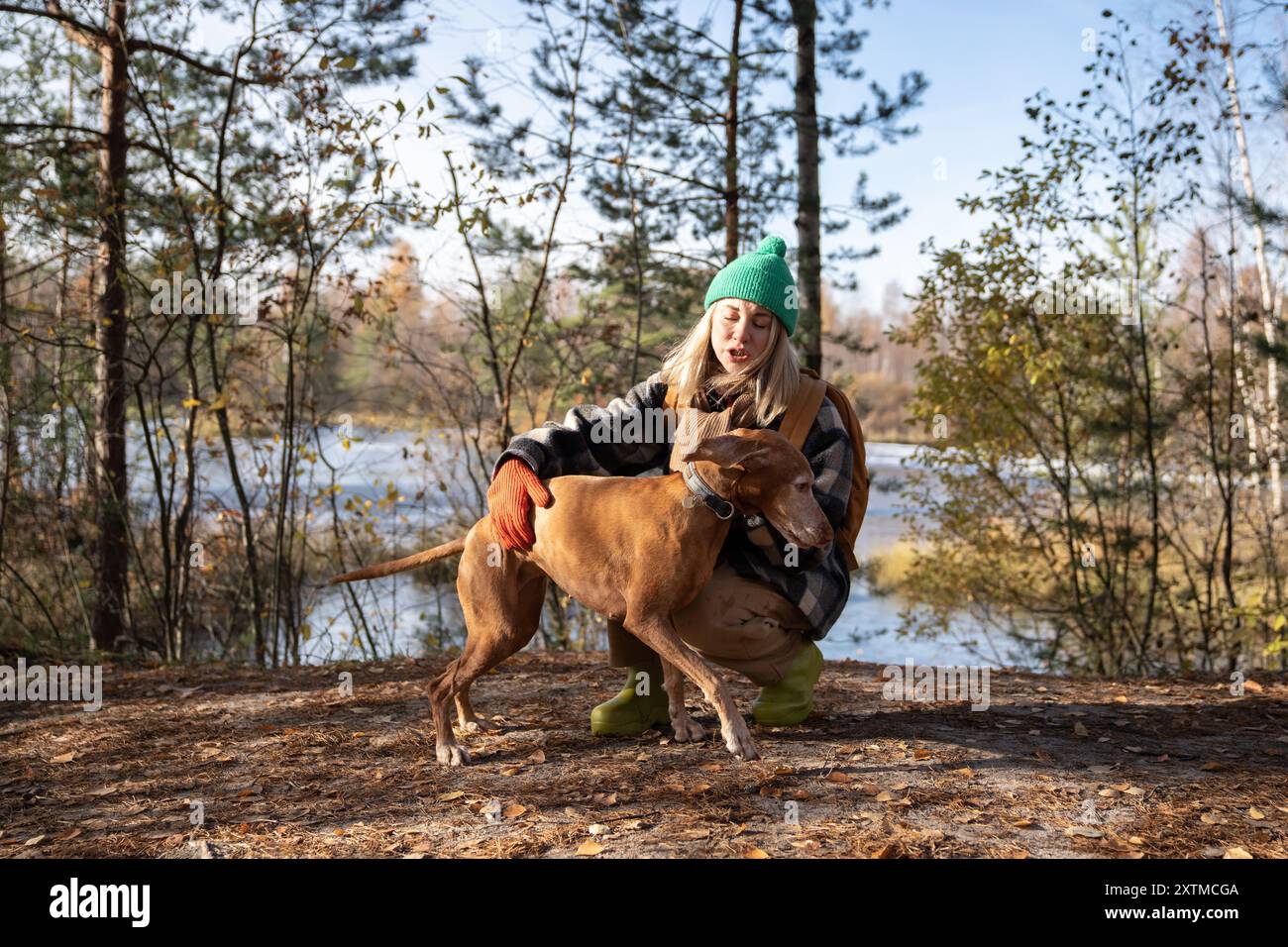 Il cane cattivo non obbedisce ai comandi del proprietario di una donna di mezza età che cammina nel parco vicino allo stagno. Foto Stock