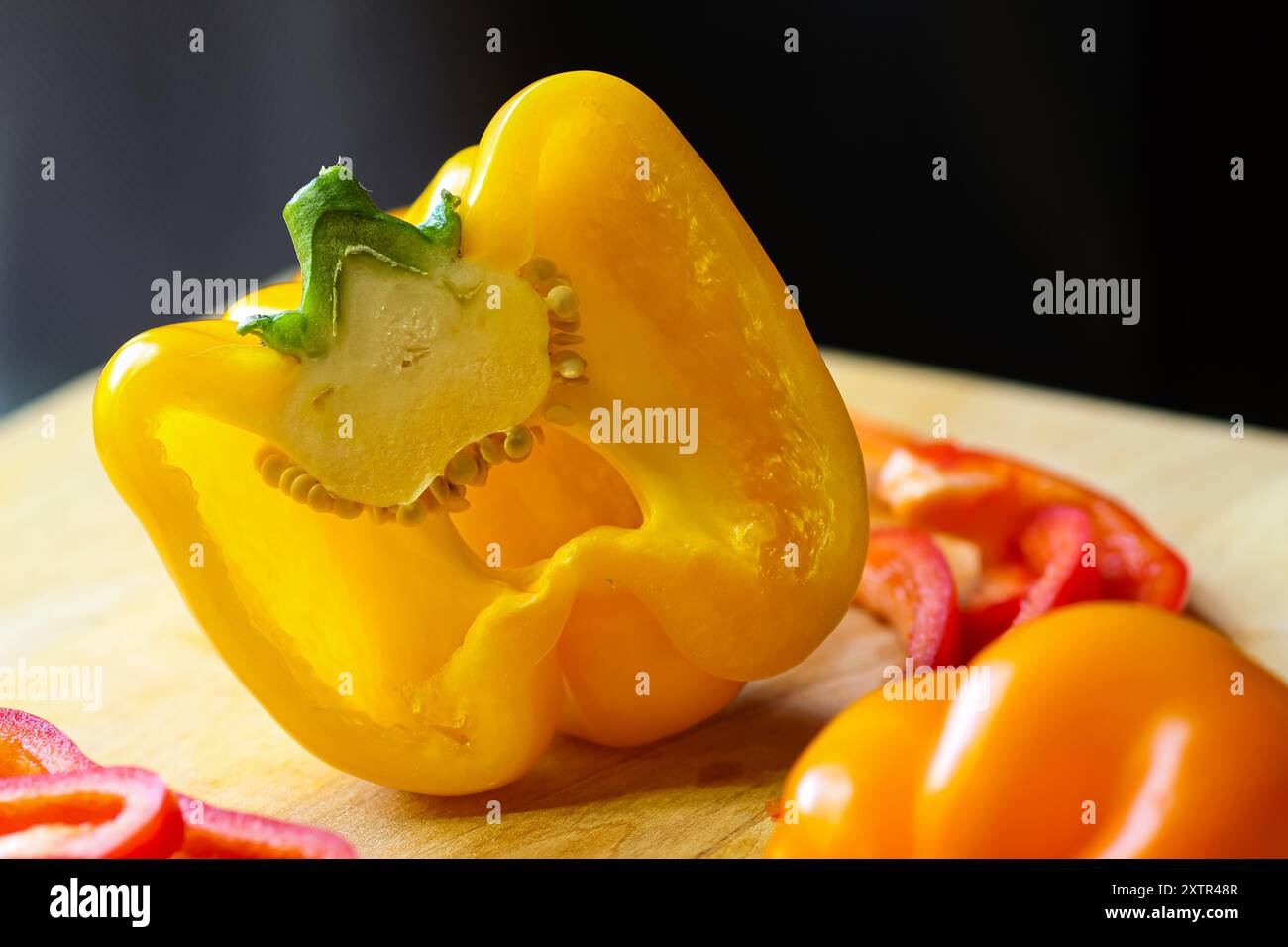 Peperoni tagliati a fette su tagliere in legno con coltello Foto Stock
