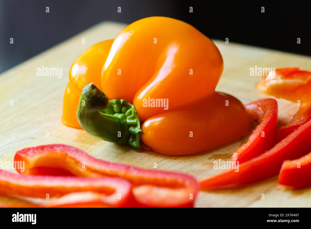 Peperoni tagliati a fette su tagliere in legno con coltello Foto Stock