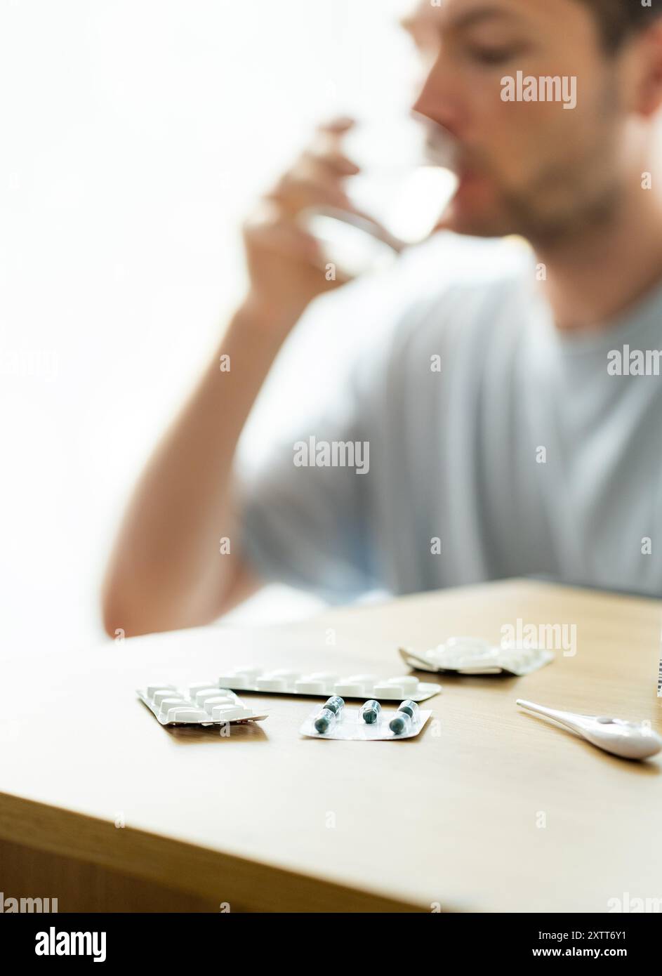 l'uomo prende la medicina, il paziente beve pillole, legge prescrizione medica, bolle con pillole sul tavolo Foto Stock