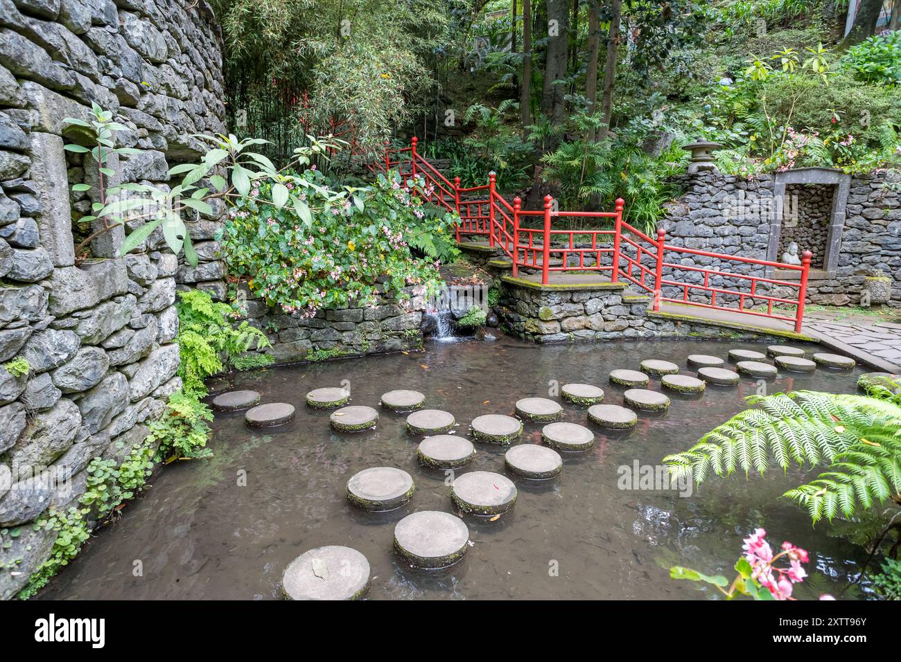 Un bellissimo passaggio pedonale di pietre circolari si estende su un piccolo stagno nei giardini del Monte Palace vicino a Funchal, Madeira, visto il 31 luglio 2024. Foto Stock
