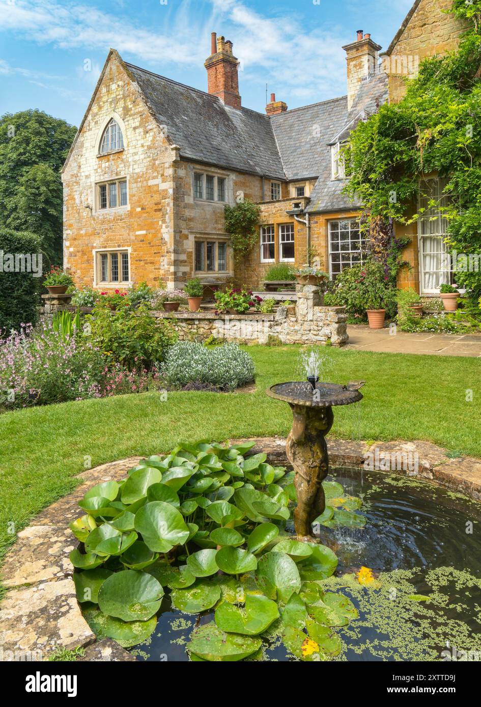 Piccolo laghetto ornamentale con fontane e vasca per uccelli, Coton Manor House and Gardens in Summer, Northamptonshire, Inghilterra, Regno Unito Foto Stock