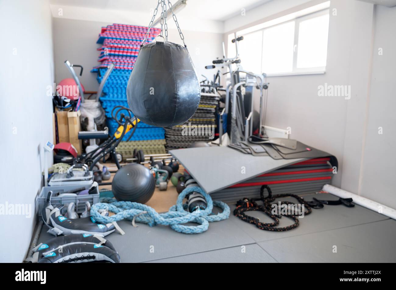 Sala dotata di varie attrezzature per l'allenamento, tra cui tappetini, borse da boxe, kettlebell e palle per esercizi. Spazio organizzato per supportare un'ampia gamma di WO Foto Stock Sala dotata di varie attrezzature per l'allenamento, tra cui tappetini, borse da boxe, kettlebell e palle per esercizi. Spazio organizzato per supportare un'ampia gamma di WO Foto Stock