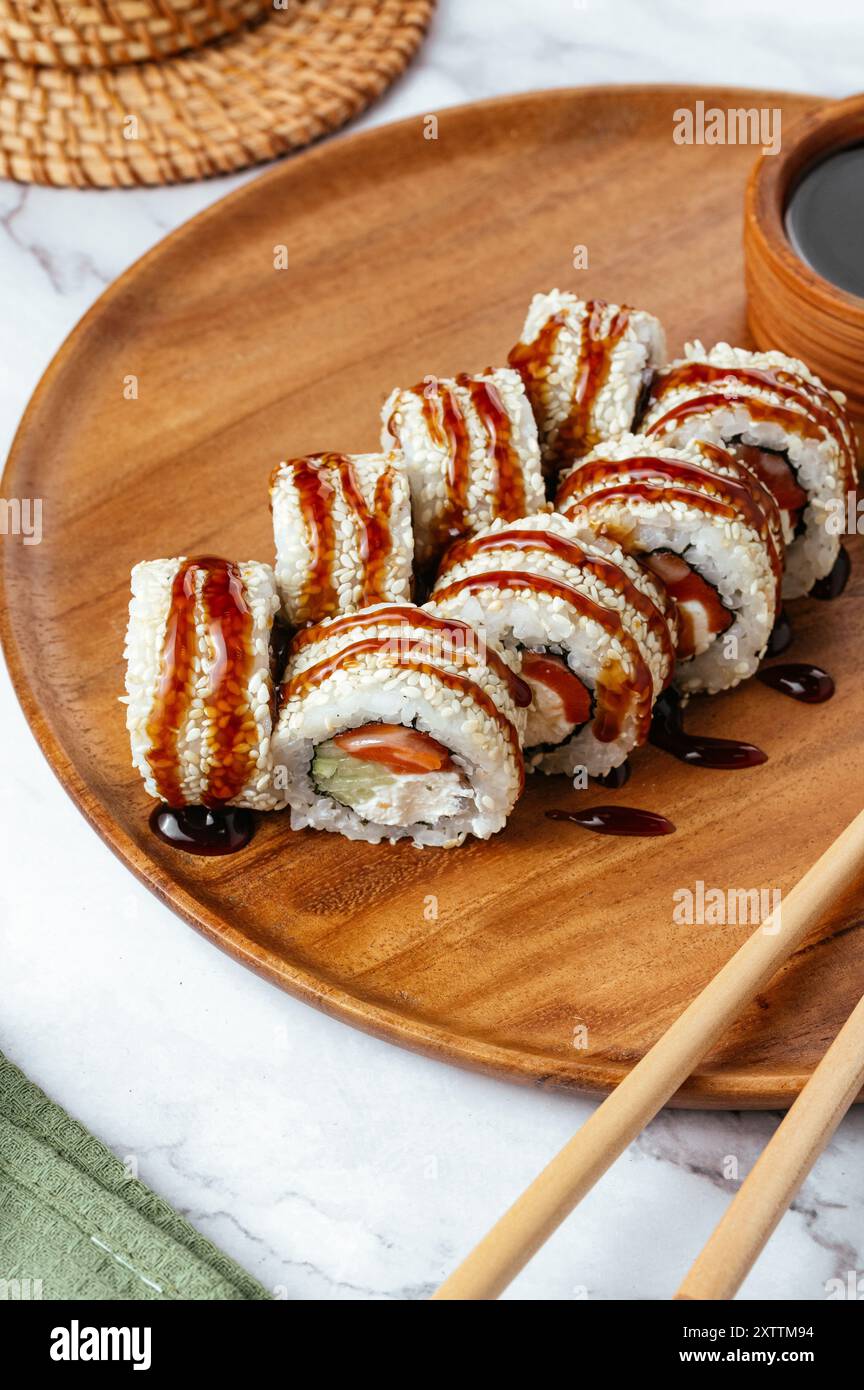 Sushi roll giapponese con cetriolo, salmone e salsa unagi Foto Stock