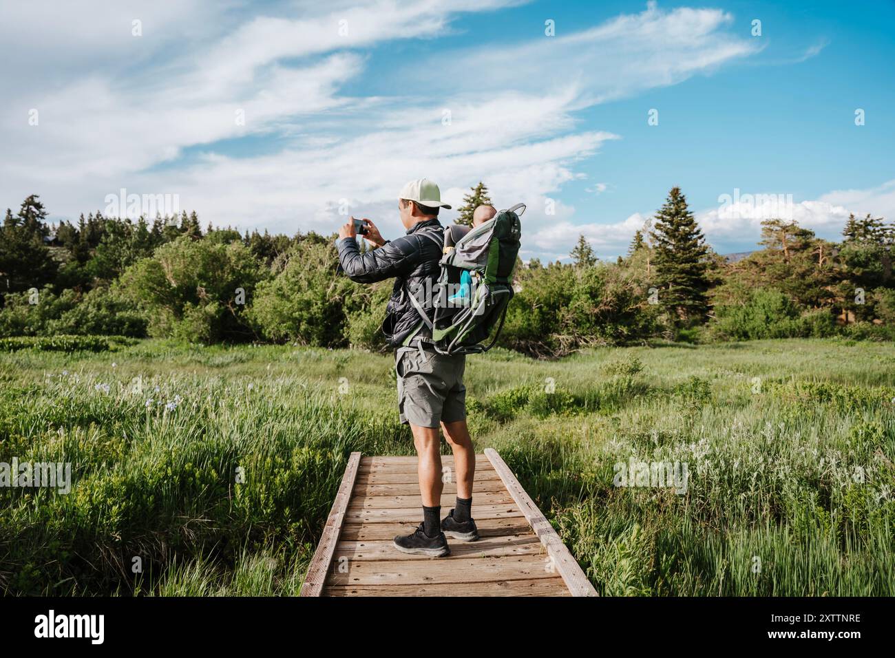 Uomo che scatta una foto della zona panoramica con il bambino nello zaino Foto Stock