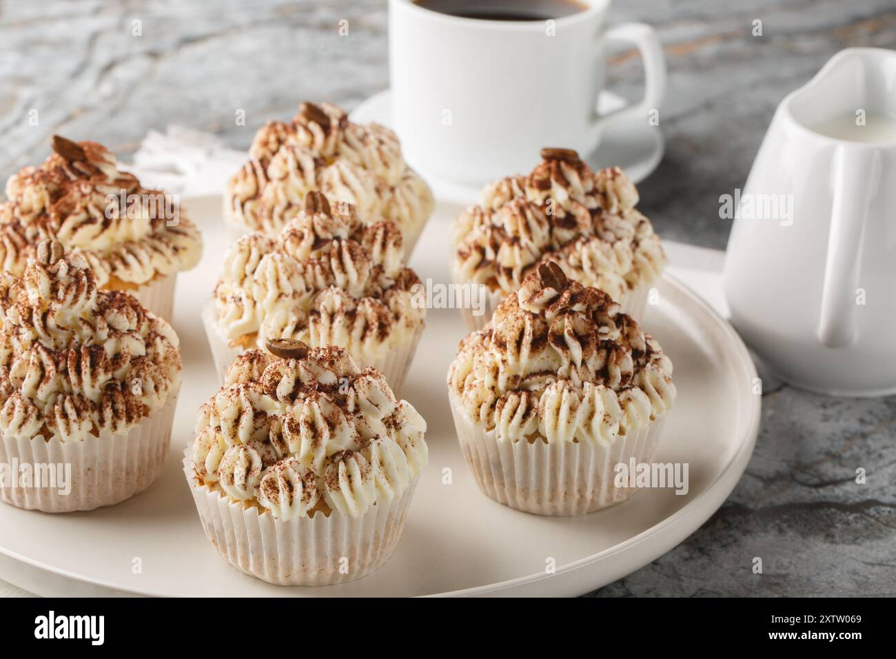 I cupcake tiramisù sono composti da deliziosi cupcake di mandorle e caffè, ricoperti da un primo piano di crema di burro mascarpone sul piatto del tavolo. Ho Foto Stock