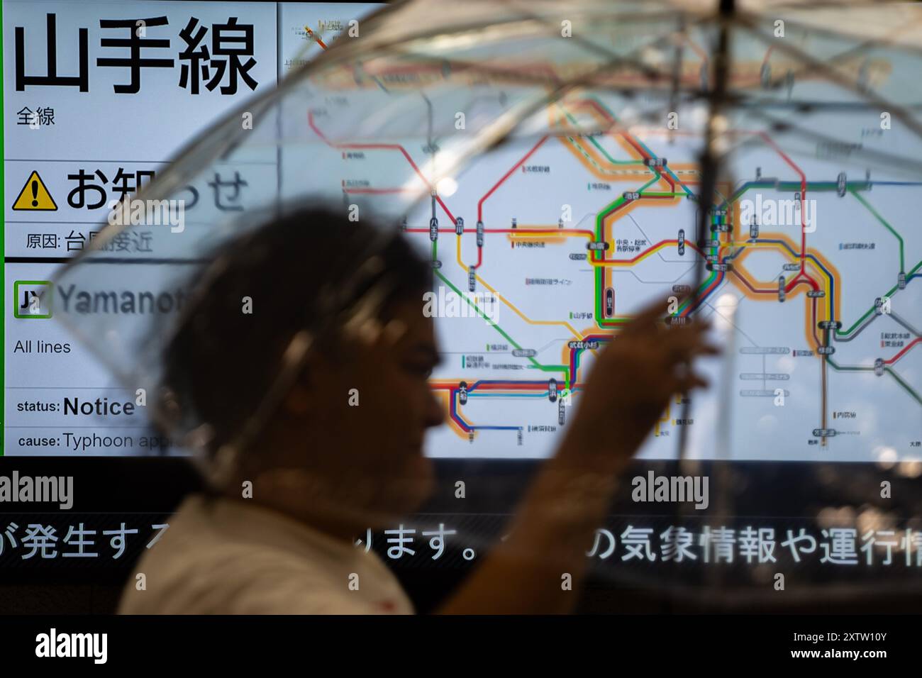 Tokyo, Giappone. 16 agosto 2024. Un pedone passa uno schermo che visualizza le informazioni sul traffico a Tokyo, Giappone, 16 agosto 2024. Ampil, il settimo tifone dell'anno, ha colpito il Giappone venerdì, forzando la cancellazione dei servizi di trasporto pubblico. Crediti: Zhang Xiaoyu/Xinhua/Alamy Live News Foto Stock