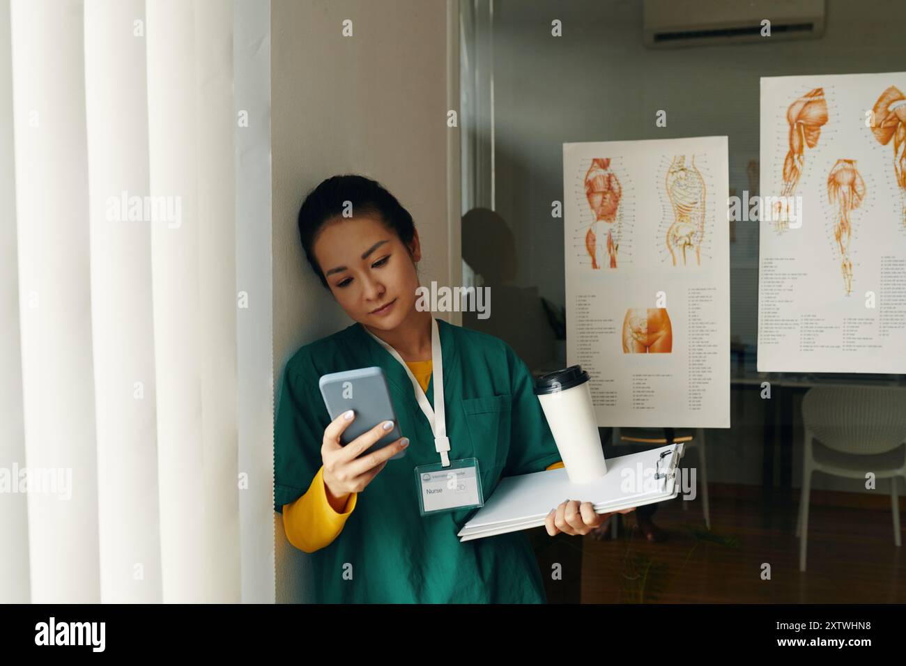 Professionista medico asiatico che tiene appunti e caffè Foto Stock